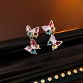 Macro shot of colorful zircon butterfly earrings with gold plating on wood texture - Gold