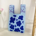 Light blue knitted tote bag with deep blue floral pattern and purple woven handles - Floral Leaf Blue