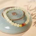 Primer plano de pulsera de jade Hetian sintético con cuenta dorada en plato celadón - Pulsera de Jade Hetian Ágata Roja del Sur Cera de Abeja