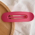 Close-up of a rose red matte hair clip with a smooth oval design on a wooden tray - Matte Peach Red