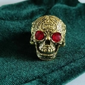 Close-up of vintage skull ring with red gemstone eyes and intricate floral carvings - Red Eye Carved Antique Gold Skull