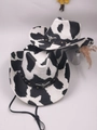 Western cowboy hat featuring black and white cow print with bull skull buckle and chin strap - Cow Print/Bull Skull Decor