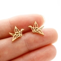 Minimalistische gouden origami kraanvogel oorknopjes voor dames getoond op een vinger - Goud