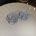 Macro shot of silver flower earrings with sparkling cubic zirconia on a white plate - Rose Flower Studs / Silver