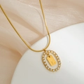 Detailed macro of gold plated oval pendant with micro-paved crystals and letter L - L