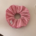Nahaufnahme des rosa-weiß gestreiften Haargummis mit Schleifenetikett auf beige Stoff - Rosa