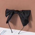 Detail showing the large black satin bow hair clip with smooth fabric texture and elegant finish - Black (Headband)