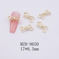 Detail of 17x8.5mm gold ribbon nail charm on pink cat-eye polish and textured fabric - Gold Bowknot-9650