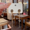 Detalle de pendientes largos dorados con borlas y piedras grises redondas talladas - Borla de Tres Cadenas de Gema Ahumada (A1000) / Dorado