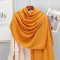 Detail of ginger yellow cotton linen scarf showing its soft texture and drape over a beige coat - Yellow