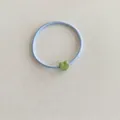 Macro di un elastico per capelli celeste con un ciondolo a forma di cuore verde opaco - Blu