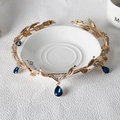 Dettaglio corona da sposa dorata con strass blu a goccia posizionata su vassoio - Oro con pietra preziosa blu reale