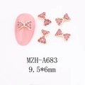 Macro detail of gold bow nail charms with pink zircons and 9.5x6mm size measurement - A683