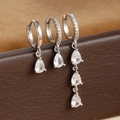 Close-up of three silver water drop earrings with clear zircon stones on soft suede - Silver-White