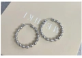 Makroaufnahme von silbernen Perlenohrringen mit einer polierten, spiegelnden Metalloberfläche - Perlenreifen-Stil / Silber