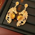 Dettaglio ravvicinato di orecchini a testa di cavallo dorati con gemme ambrate e strass - Oro Con Gemma Ambra (Perno in Argento)