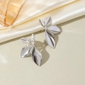 Detailed view of silver leaf stud earrings on elegant silk with amber glass accents - Silver-Style D