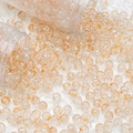 Close-up of translucent orange floral glass beads scattered from clear containers - 8mm Spotted Beads / Orange