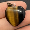 Handheld view of heart-shaped tiger eye stone pendant with silver metal clasp - 20mm / Tiger's Eye
