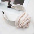 Close-up of a beige satin padded headband featuring a large fabric rose with silk texture - Off-white