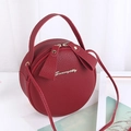Chic burgundy round crossbody bag with litchi grain texture and gold metal logo - Burgundy