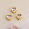 Close-up of three pink heart zirconia beads with gold plated copper frame for DIY jewelry - Pink