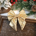 Sparkling gold sequined Christmas bow ornament on rustic wooden tray with holiday decor - Gold