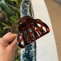 Macro detail of amber tortoise shell hair claw clip showing glossy finish and texture - Glossy Red Brown