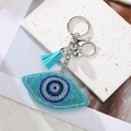 Close-up of heart-shaped evil eye pendant with blue crystals and silk tassel detail - Lake Blue Eye Silver Clasp