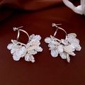 Dettaglio di orecchini d'argento con petali di fiori madreperla su tessuto rosso - Petali Perlati Bianchi Argento (5# Perno in Argento)