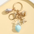 Detailed close-up of luminous conch and starfish keychain with gold lobster clasp - Blue