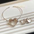 Ensemble collier et boucles d'oreilles cœur en argent poli sur un plateau blanc texturé - Ensemble Cœur Argent
