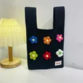 Black knitted tote bag featuring six colorful 3D crochet flowers and white brand tag - Colorful Flowers On A Black Background