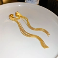 Macro-opname van een gouden oorklem met kwastjes en elegante kettingen op wit keramiek - Clip-oorbellen / Goud (Enkel)