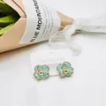 Elegant gold-rimmed light blue camellia studs on a stainless steel card display - Aqua
