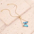 Dettaglio del ciondolo a farfalla dorata con cristallo sfumato blu e chiusura scorrevole - Blu Scuro (2#)