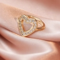 Detailed close-up of a gold heart-shaped open ring with cubic zirconia on pink silk - Large White Heart/Gold Hollow