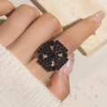Close-up of a bold black rhinestone ring in a hollow geometric floral pattern on a finger - Adjustable Open / Black Hollow Floral Style (6014BK)