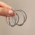Vista detallada de pendientes de aro triple plateados con un diseño minimalista por capas - Estilo de Aros de Triple Capa / Plateado