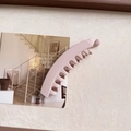 Dettaglio del fermaglio a banana rosa opaco su sfondo beige con cartolina decorativa - Rosa carne