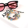Detail of colorful woven bohemian eyewear strap with rubber loops on a white book - US 1