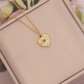 Detalle del collar de corazón martillado dorado con circonita azul en caja beige - Corazón De Lava Martillada (2#)