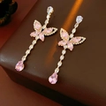Close-up of pink crystal butterfly drop earrings with cubic zirconia on brown leather - Pink (Silver Earring Post-Gold)