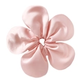 Macro shot of oversized pink satin floral scrunchie with smooth silk texture - Pink