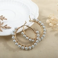 Detail of handmade gold hoop earrings with silver-grey pearls on white relief plate - Light Gray