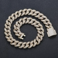 Macro shot of 18mm gold Cuban link necklace with micro-pave zircons on black surface - 16" / Gold