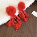 Detail view of red pompom earrings with beaded charms and long cotton fringe tassels - Hairball Tassel Style / Red