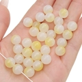 Hand hält cremegelbe Acrylperlen für DIY-Schmuckherstellung und Halsketten - 8mm/50Stk/13g / Gelbe Serie