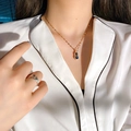 Collana a forma di arachide dorata con pietre blu su camicia di seta bianca - Arachide bicolore zaffiro in oro rosa