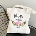 Nurse Graduate 2021 white canvas tote bag with pink flower print on a black mesh chair - Style C4 (No Inner Pocket/No Zipper)